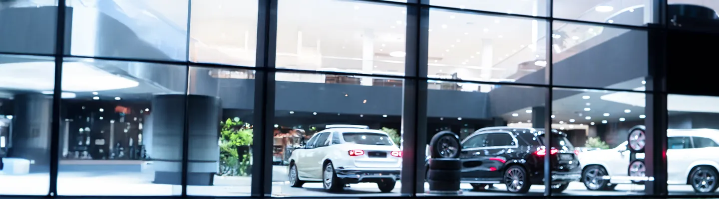 Blurred background with car dealership exterior.